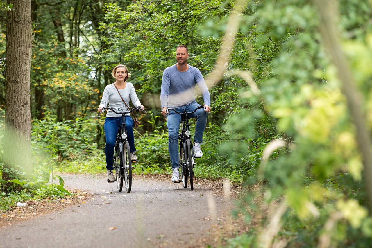Stel fietst door een groen bos nabij De Pastorie Zeeland